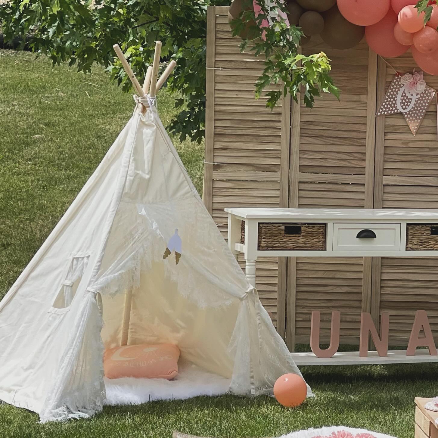 Boho lace teepie with peach balloon arch and personalized name backdrop